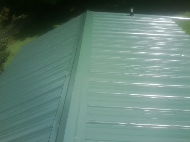 New green metal panels meeting at the ridge of a roof — Flat Roof Repair work by our crew in East Carbon