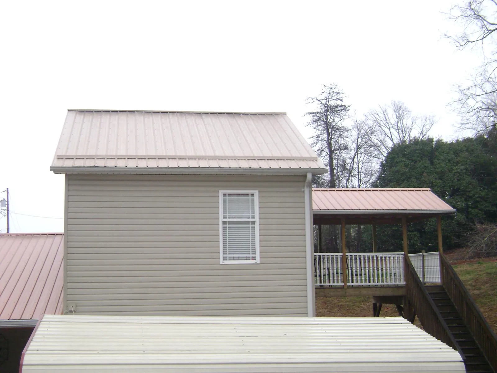 Tan metal roofs on a two story addition and attached porch, from a Roof Replacement job in East Carbon