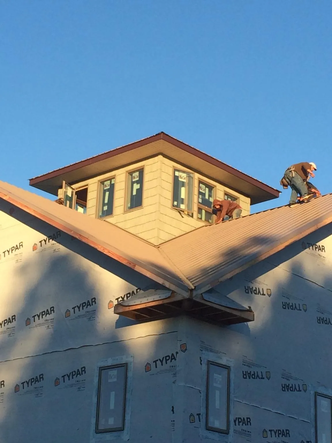 Roofers working around a rooftop cupola on a new metal roof at sunset — Roof Waterproofing in East Carbon by Roofing Brothers